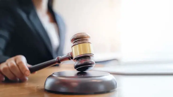 Woman in black blazer pressing a wooden gavel against a table