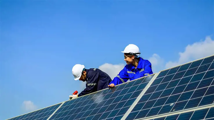 Man and woman in white hard hats installing solar panels